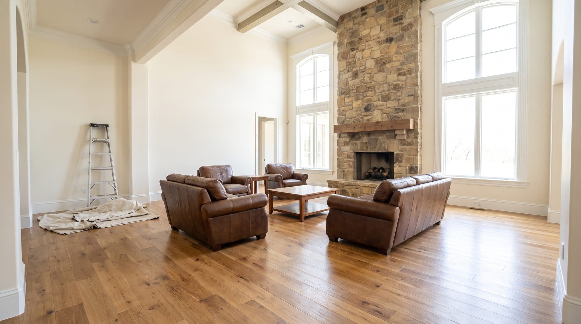 Freshly painted great room with warm-white walls, crisp white trim, and a stone fireplace