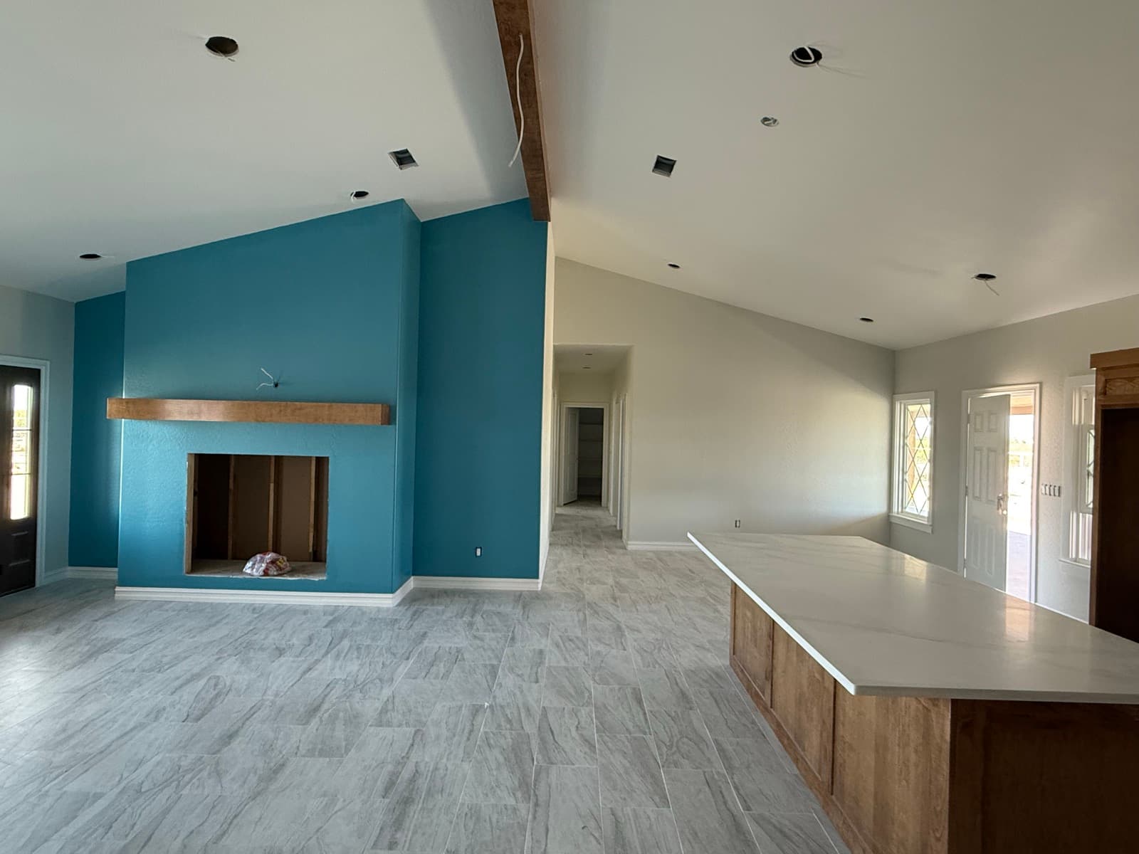 Open-concept living room with a blue accent fireplace wall